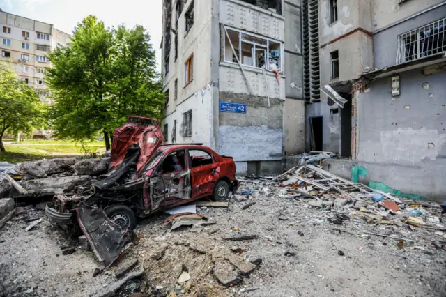 A destroyed car is pictured in front of a residential building following a Russian rocket attack in the Saltivka district of Kharkiv