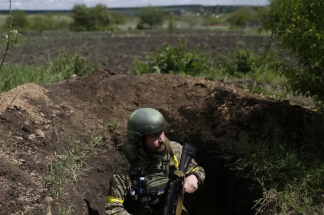 A Ukrainian serviceman uses a trench as an observation point at a frontline area in Ruska Lozova, a village retaken by the Ukrainian forces in the Kharkiv region