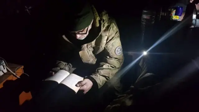 A member of Mariupol's unit of the Ukrainian Sea Guard reads inside a bunker inside the Azovstal steelworks