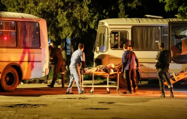 A wounded service member of Ukrainian forces from the besieged Azovstal steelworks in Mariupol is transported on a stretcher out of a bus, which arrived under escort of the pro-Russian military in Novoazovsk, Ukraine, on 16 May 2022