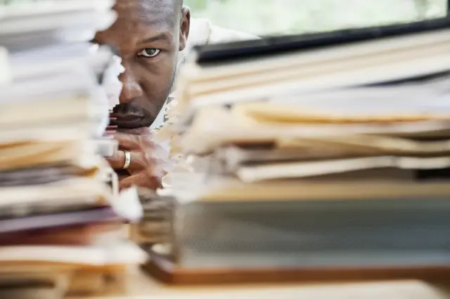 Stock image of man behind pile of documents