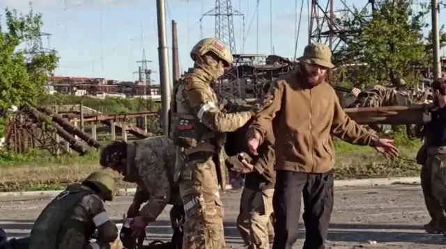 A man believed to be a Ukrainian fighter is searched by pro-Russian military outside the Azovstal steelworks