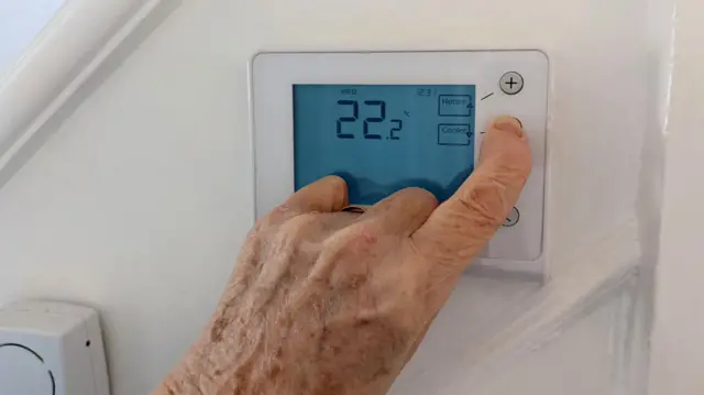 Hand turning down a thermostat