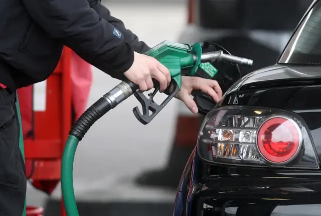 A person using petrol pump at a petrol station