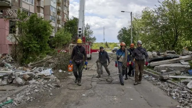 Ukrainian workers remove dangerous parts from the vicinity of a building which was damaged in a shelling in Kharkiv, Ukraine, 17 May 2022.