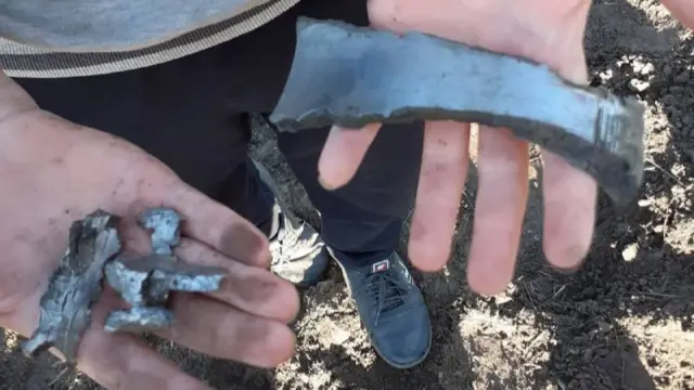 Hands holding what appears to be shrapnel