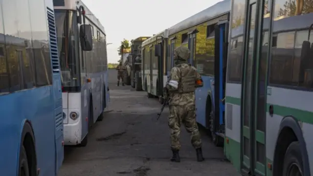 Donetsk People"s Republic (DPR) militia guard waiting by buses