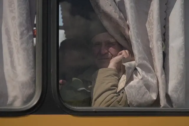 An old man looks out of the window of a vehicle on its way to Zaporizhzhia