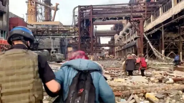 Civilians are helped over rubble at the steelworks plant, which has been under heavy Russian bombardment