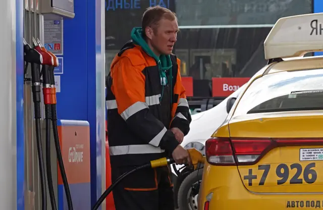 A gas station worker fills a car at a Gazprom Neft gas station in Russia's capital Moscow