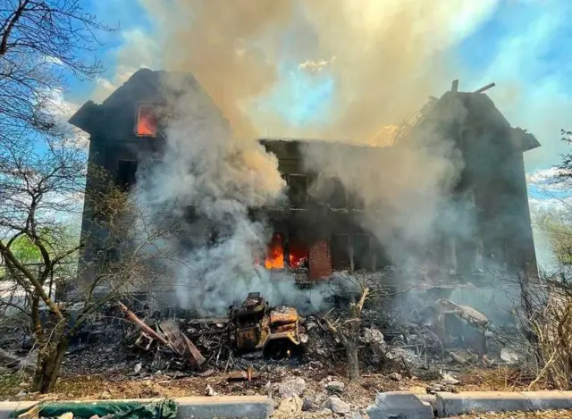 A large burning school covered with flames and smoke