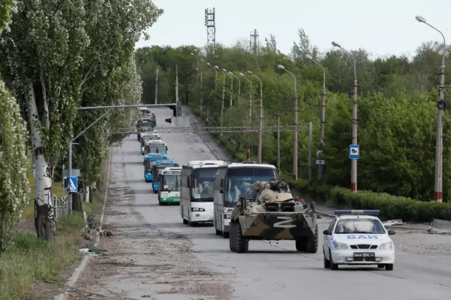 A Russian tank escorts several buses