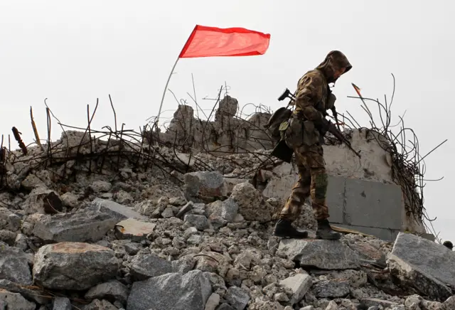 A serviceman of the self-proclaimed Donetsk People's Republic walks past a pile of rubble