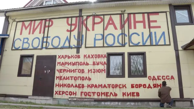 A man paints slogans on a shopping centre he owns