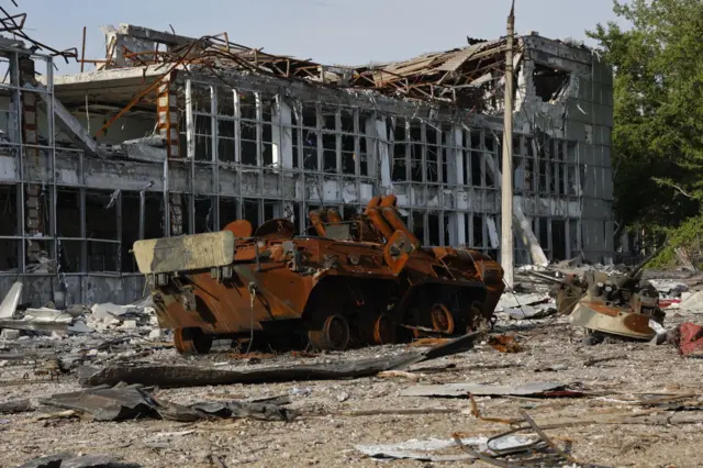 View of a damaged military vehicle and buildings in Mariupol