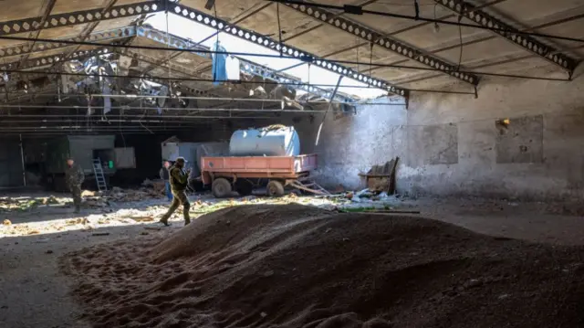 Ukrainian soldiers inspecting a grain warehouse earlier shelled by Russian forces earlier in May