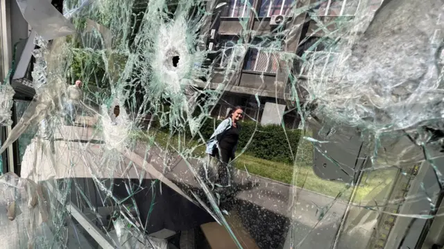 A building is reflected in a shop window in a residential area after a shelling  in Kharkiv