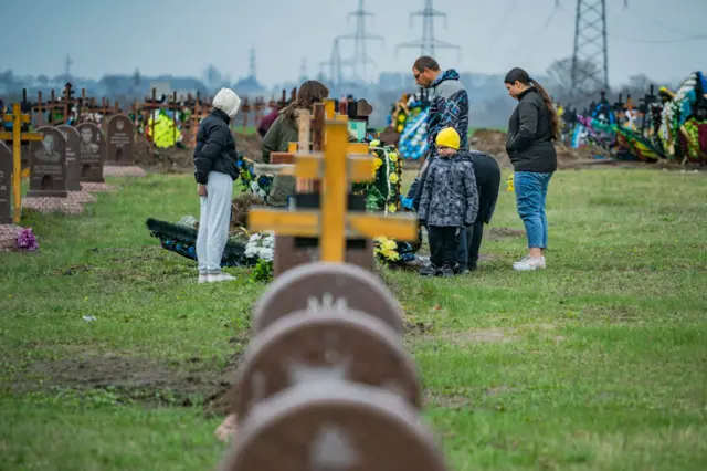 A family in Dnipro stands by the grave of a soldier relative killed in the Russian war