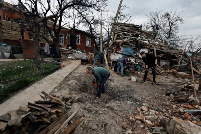 Locals try to clear up rubble on the outskirts of Chernihiv