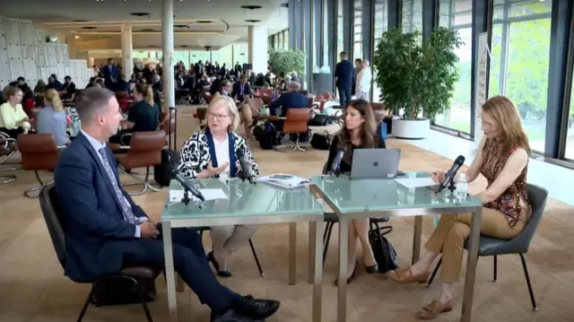 WHO experts talk around a table in a busy hall