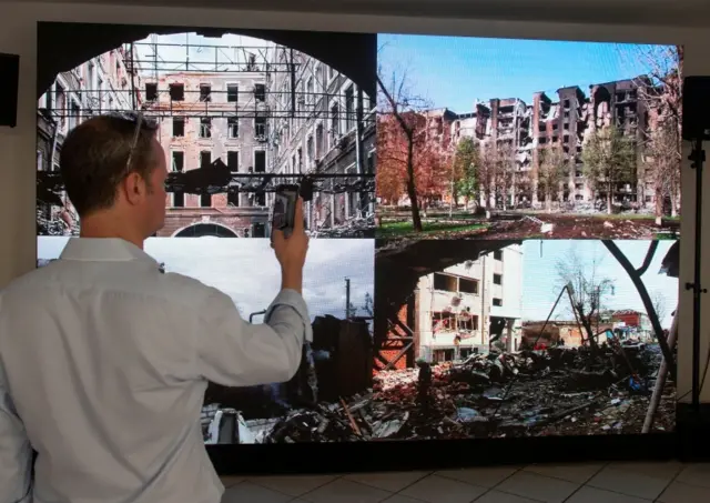 A man takes a picture of an exhibition at the former "Russia House", which Ukrainian artists have transformed into a "Russian War Crimes House" during the World Economic Forum in Davos, Switzerland. Photo: 22 May 2022