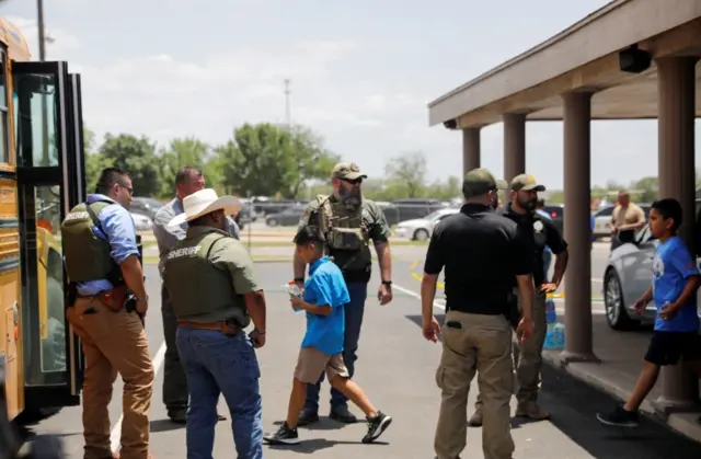 children get on a school bus as law enforcement personnel guard the scene of a suspected shooting near Robb Elementary School in Uvalde, Texas, U.S. May 24, 2022.