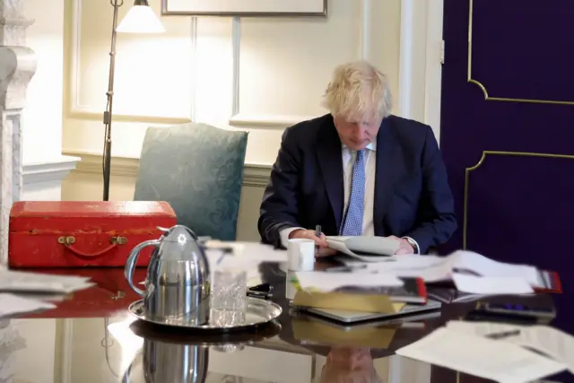 Boris Johnson reads Sue Gray's report with his red ministerial box by his side