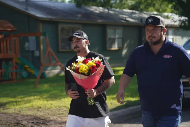 A Uvalde resident brings flowers to the makeshift memorial outside Robb Elementary School