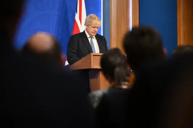 Johnson looks down at the lectern as he answers questions from the press