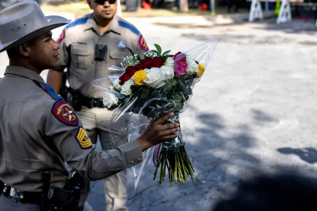 A Texas State Trooper receives flowers for the victims of the shooting