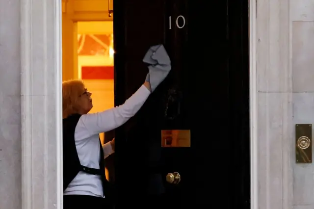 A worker polishes the door of No 10 Downing Street