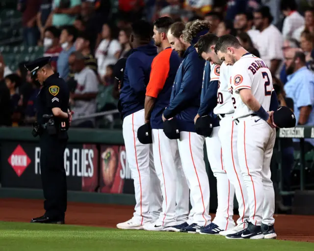 Members of the Houston Astros bow their heads during a moment of silence before a game there against Cleveland