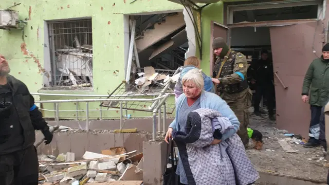 A woman among the walking wounded in the aftermath of an air strike on a maternity and children's hospital, Mariupol in March