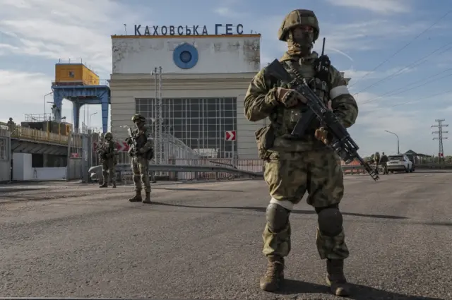 Russian servicemen stand guard near the Kakhovka hydroelectric plant