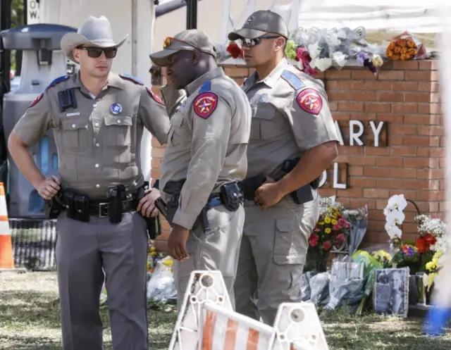 Texas Highway Patrol officers stand near a memorial in Uvalde