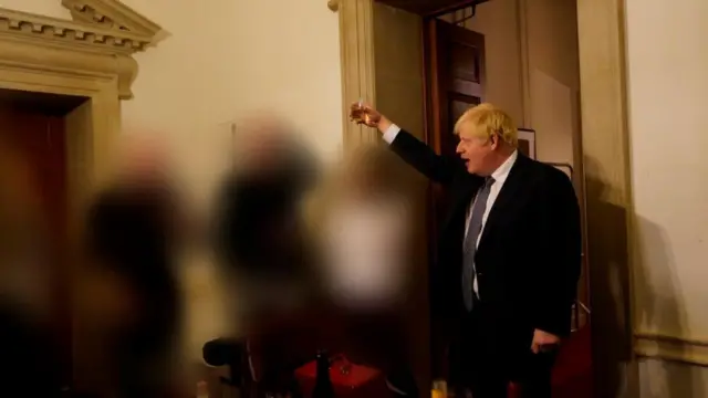 Prime Minister Boris Johnson holds a drink aloft at a gathering in 2020