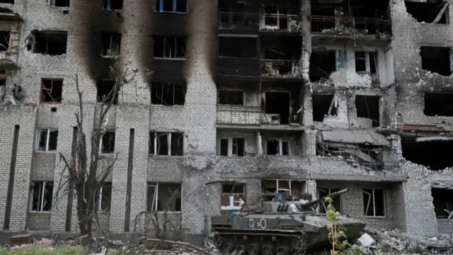 A Russian BMD-4M infantry fighting vehicle is seen in front of an apartment building heavily damaged during Ukraine-Russia conflict in the town of Popasna in the Luhansk Region