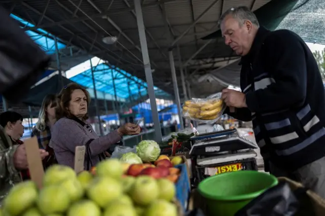 A woman buys bananas at a market