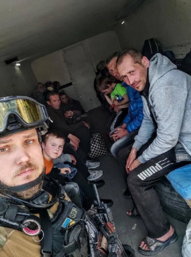 A Ukrainian police officer with evacuated Lysychansk residents