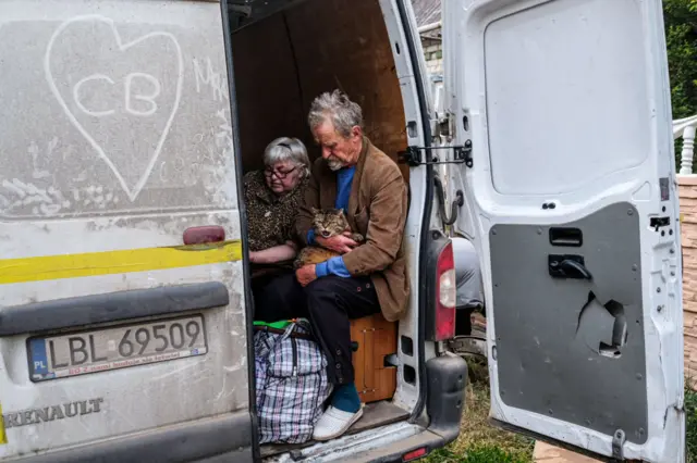 A man and woman are glimpsed in the back of a van