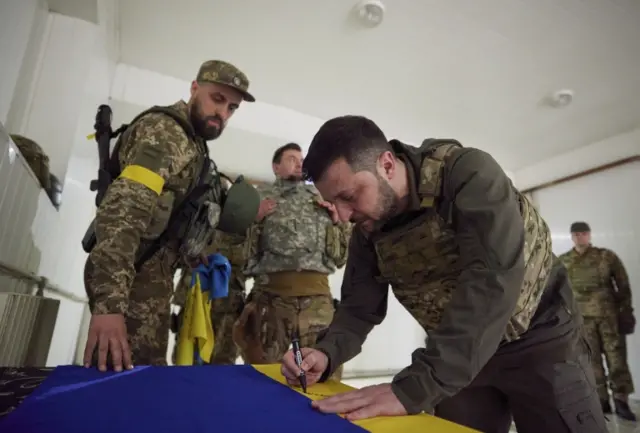 Ukrainian President Volodymyr Zelensky signs a national flag during his visit to Kharkiv