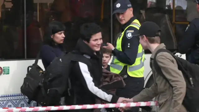 A young boy was seeing shaking hands with another across the tape dividing evacuees from onlookers and media