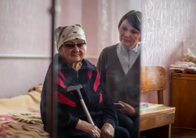 Two women sat together on the edge of a bed