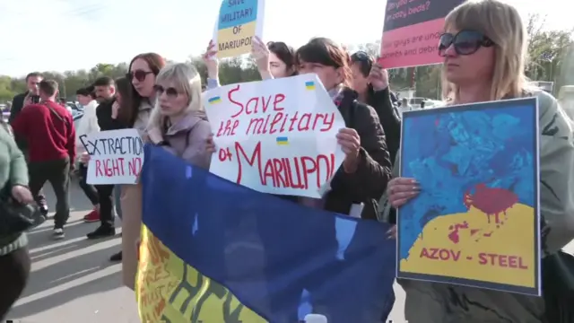 Civilians hold signs asking for the safe removal of Ukrainian troops who remain trapped in the steel plant