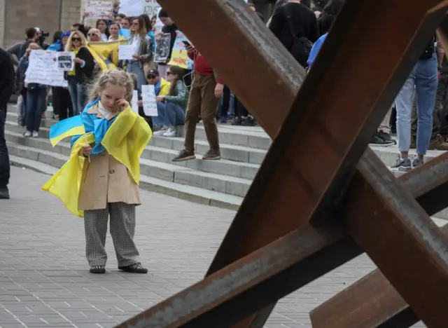 A girl draped in the Ukrainian flag at the protest