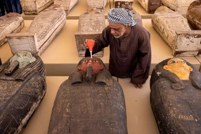 A man brushing dust off an Egyptian coffin