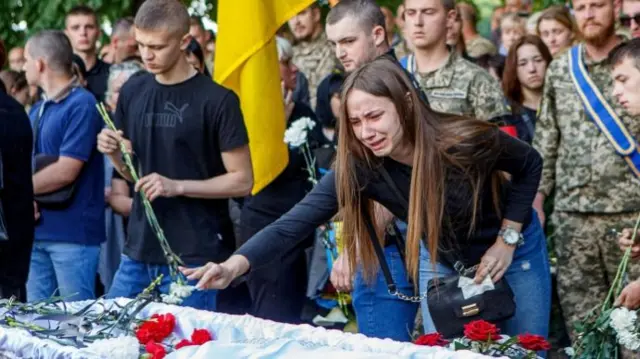 A mourner reacts as she places flowers on the coffin of Denis Kofel, a Ukrainian serviceman who was killed during Russia"s invasion, during his funeral in Uzhhorod, Zakarpattia region, Ukraine, May 30, 2022