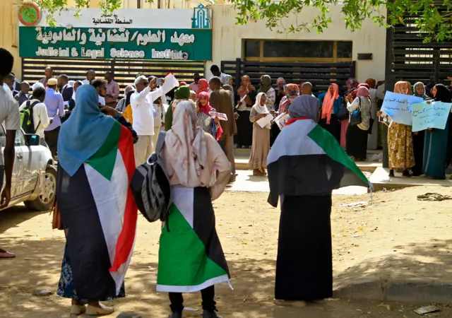 Sudanese protesters lift placards while rallying outside a court in the capital Khartoum,