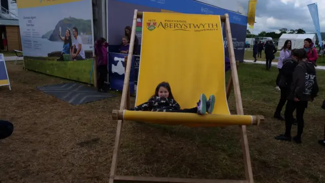 Gwen yn mwynhau hoe ar gadair anferth Prifysgol Aberystwyth