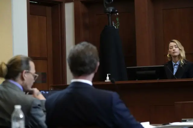 Actor Johnny Depp listens next to attorney Ben Chew as his ex-wife, actor Amber Heard, testifies at Fairfax County Circuit Court during Depp's defamation case against her in Fairfax, Virginia, on May 4, 2022